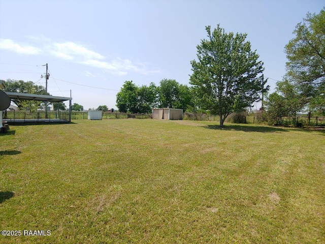 view of yard with an outbuilding, fence, and a storage shed
