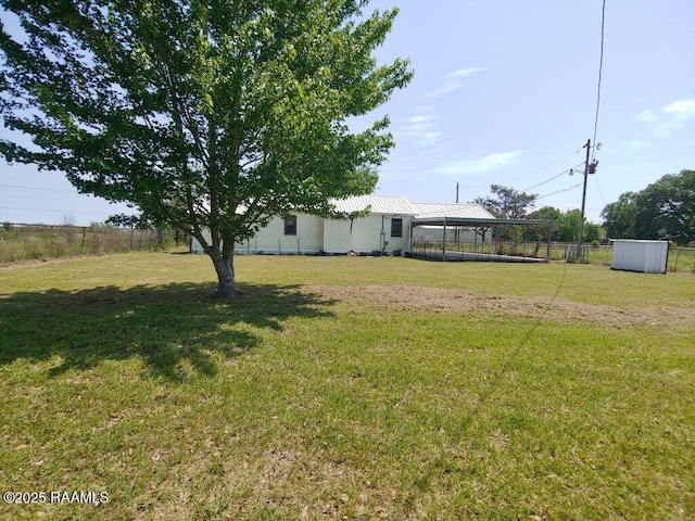 view of yard with fence, an outbuilding, and a carport