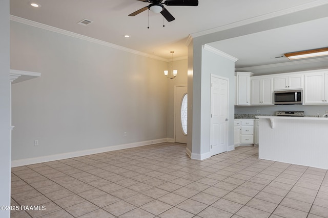 kitchen featuring crown molding, visible vents, baseboards, a kitchen bar, and stainless steel microwave