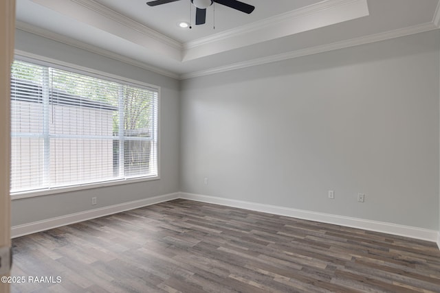 unfurnished room featuring ceiling fan, a raised ceiling, dark wood finished floors, baseboards, and ornamental molding