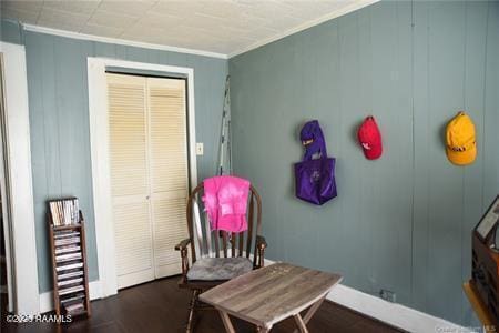 interior space with a decorative wall, wood finished floors, baseboards, and ornamental molding