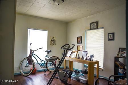 exercise area with ornamental molding and wood finished floors