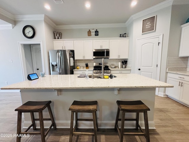 131 Wild Cherry Ln, Lafayette, LA 70508 - kitchen with appliances with stainless steel finishes, backsplash, a kitchen breakfast bar, crown molding, and white cabinets