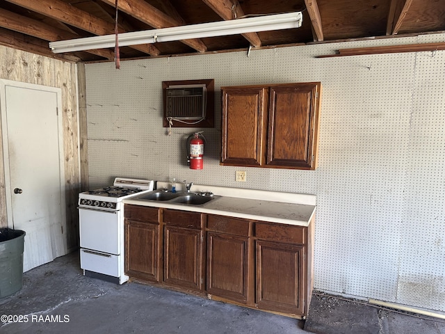kitchen with dark brown cabinets, a sink, a wall mounted air conditioner, concrete floors, and gas range gas stove