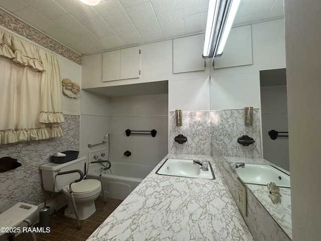 full bathroom with a sink, tile walls, toilet, and a bath