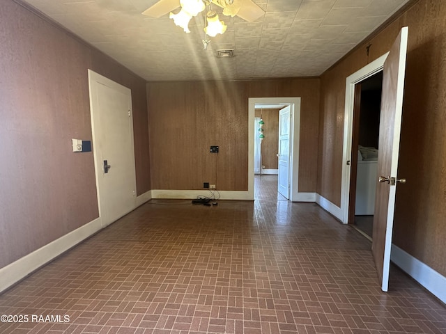 empty room featuring ceiling fan, brick patterned floor, and baseboards