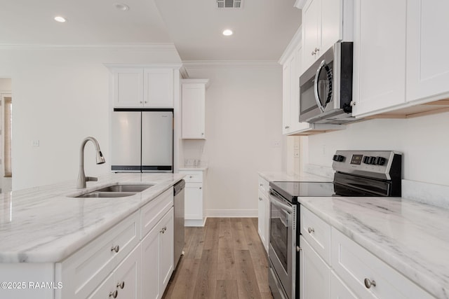 kitchen with stainless steel appliances, a sink, white cabinetry, light wood finished floors, and ornamental molding
