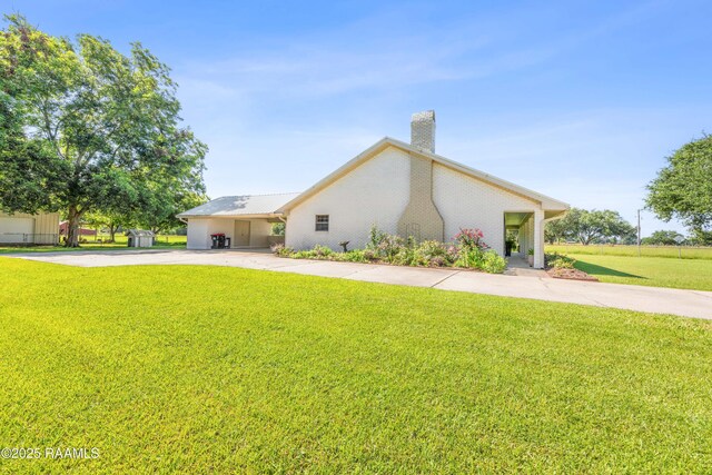 319 Roger Rd, Lafayette, LA 70507 - view of side of home with driveway, a chimney, a carport, and a lawn