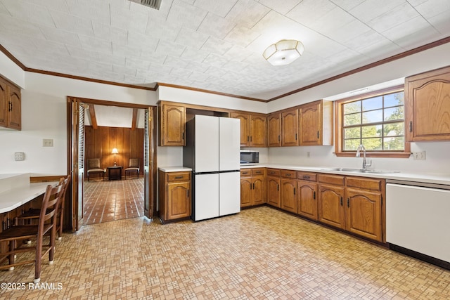 319 Roger Rd, Lafayette, LA 70507 - kitchen featuring white appliances, ornamental molding, brown cabinetry, light countertops, and wood walls