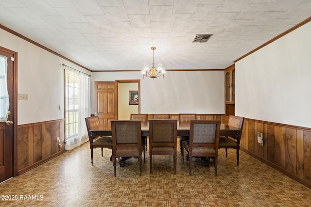 319 Roger Rd, Lafayette, LA 70507 - dining space featuring a wainscoted wall, a chandelier, wooden walls, and crown molding