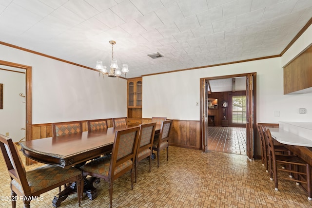 319 Roger Rd, Lafayette, LA 70507 - dining space featuring a chandelier, a wainscoted wall, wood walls, and ornamental molding