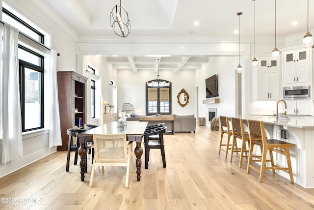 dining space with coffered ceiling, light wood finished floors, beam ceiling, and a chandelier