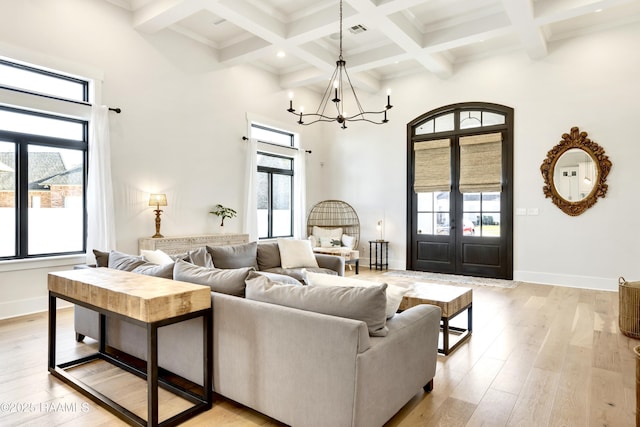 living room with french doors, a high ceiling, beam ceiling, and a healthy amount of sunlight