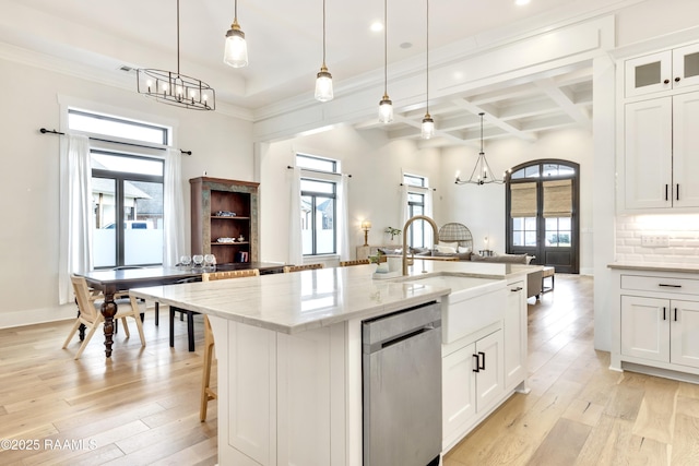 kitchen featuring light wood-type flooring, white cabinetry, light stone counters, dishwasher, and a notable chandelier