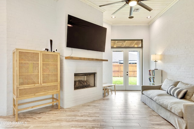 living room with crown molding, a fireplace, french doors, a ceiling fan, and wood finished floors