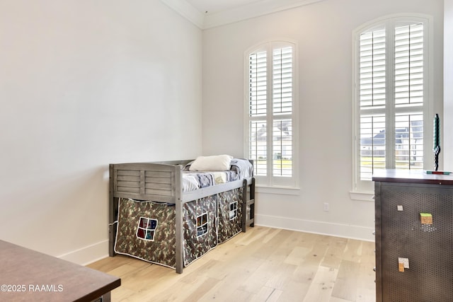 bedroom with baseboards, multiple windows, and wood finished floors