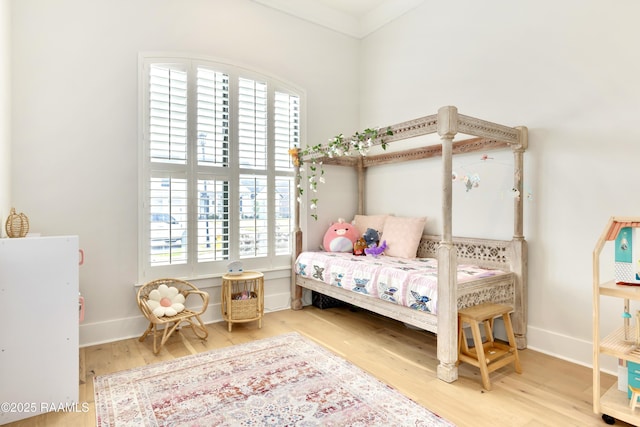 bedroom with baseboards, wood finished floors, and multiple windows