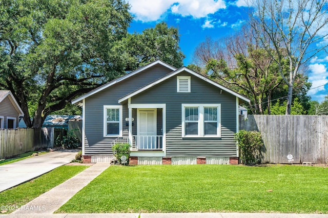 bungalow-style home with concrete driveway, fence, and a front yard