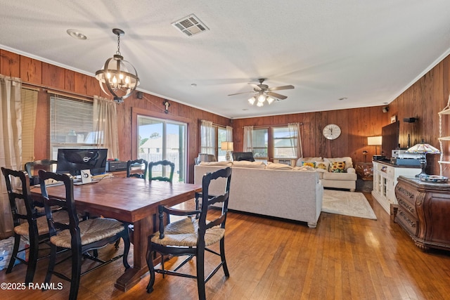 202 Sapphire Dr, Lafayette, LA 70506 - dining room featuring wooden walls, crown molding, visible vents, and ceiling fan with notable chandelier