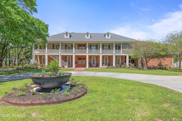 neoclassical home with a front lawn, a porch, brick siding, and french doors