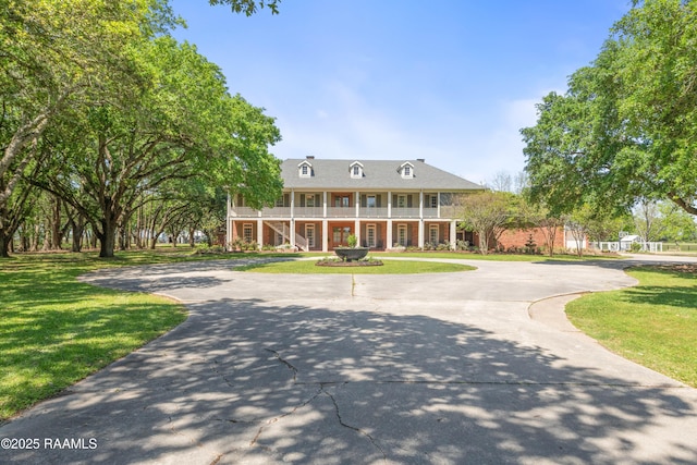 neoclassical / greek revival house with a porch, stairs, a front lawn, and brick siding