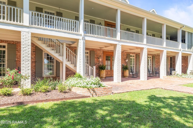 exterior space with stairway, a patio, and brick siding