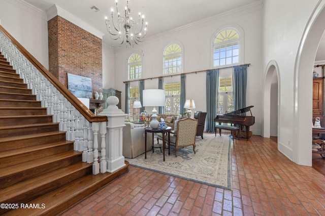 foyer entrance with crown molding, a towering ceiling, brick floor, and arched walkways