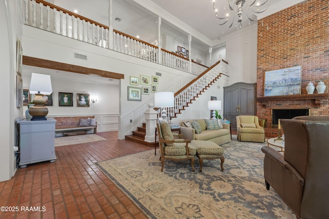 living area with brick floor, ornamental molding, visible vents, a towering ceiling, and stairway