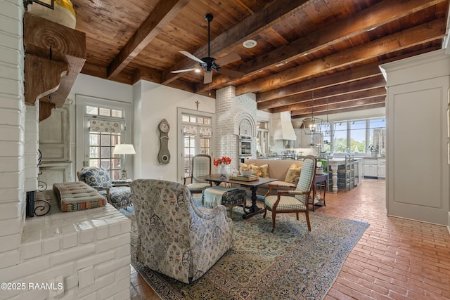 living room featuring ceiling fan, beam ceiling, brick floor, and wood ceiling