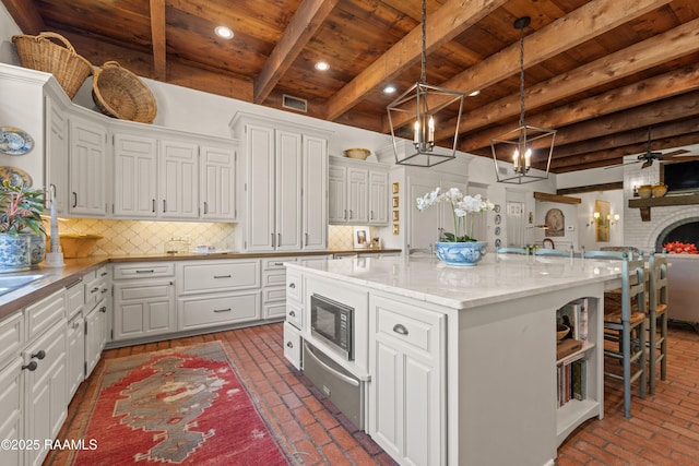 kitchen featuring a warming drawer, wood ceiling, brick floor, and white cabinetry