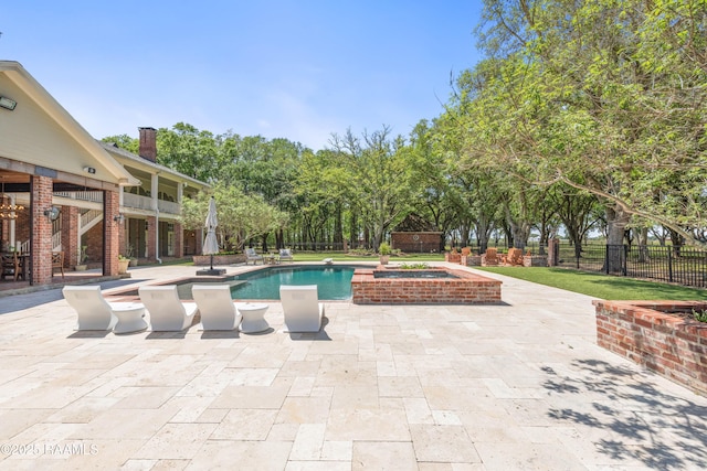 view of swimming pool featuring a patio area, a pool with connected hot tub, and fence