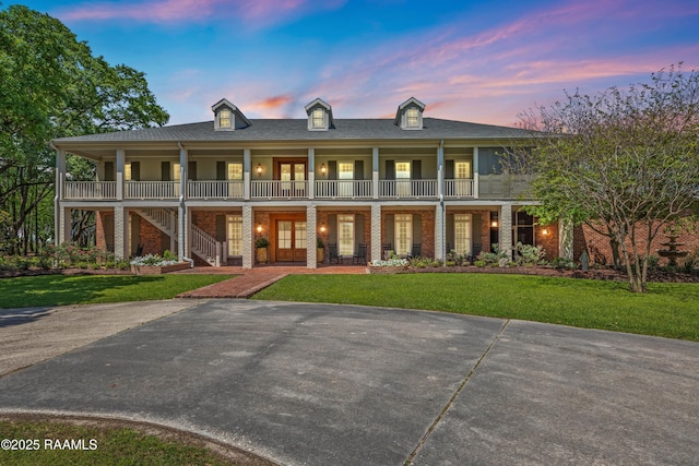 view of front facade featuring a front lawn, brick siding, and covered porch