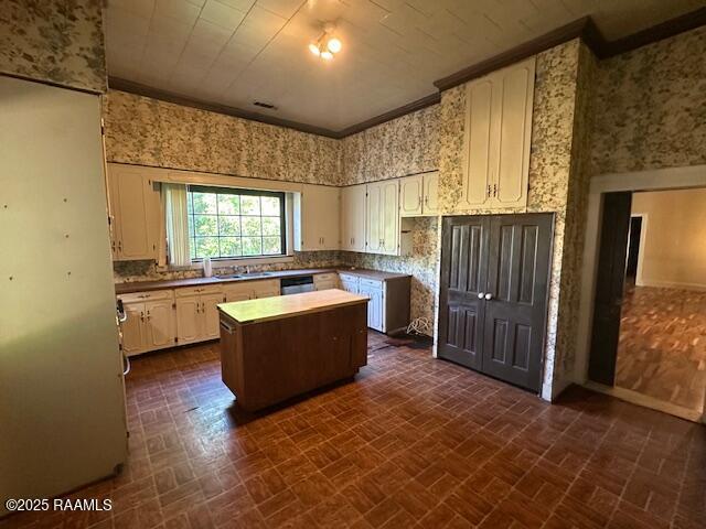 505 Fairview Ave, Abbeville, LA 70510 - kitchen with brick patterned floors, a center island, wallpapered walls, crown molding, and white cabinets