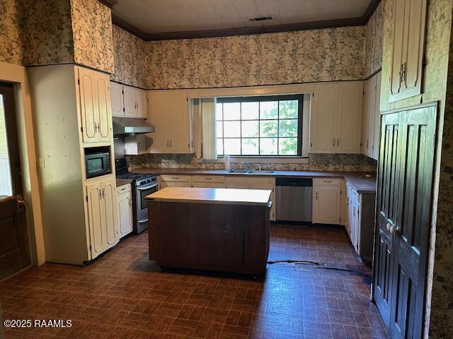 505 Fairview Ave, Abbeville, LA 70510 - kitchen featuring appliances with stainless steel finishes, under cabinet range hood, white cabinets, crown molding, and a center island