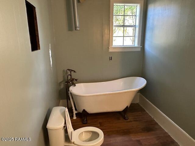 505 Fairview Ave, Abbeville, LA 70510 - full bathroom featuring wood finished floors, toilet, a freestanding tub, and baseboards