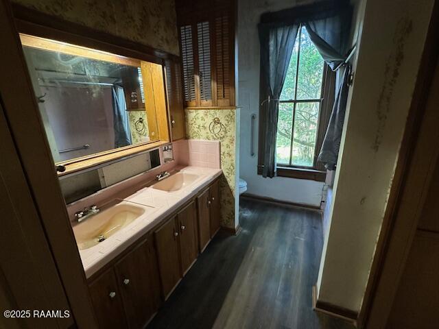 505 Fairview Ave, Abbeville, LA 70510 - bathroom featuring wood finished floors, double vanity, toilet, a shower, and wallpapered walls