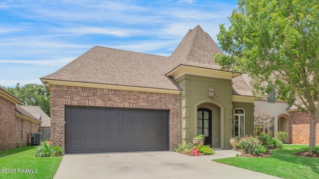 view of front of home featuring an attached garage, brick siding, driveway, central AC unit, and a shingled roof