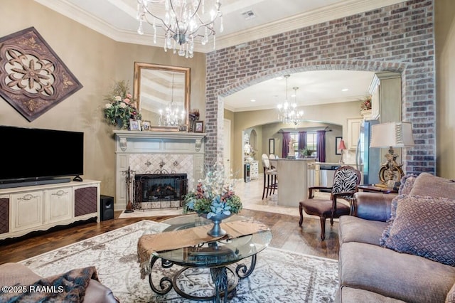 living area featuring an inviting chandelier, crown molding, dark wood-type flooring, visible vents, and arched walkways