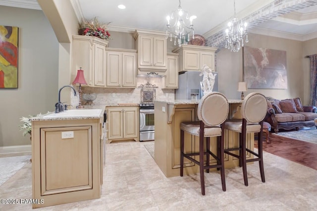 kitchen with a breakfast bar, an inviting chandelier, a sink, cream cabinetry, and appliances with stainless steel finishes