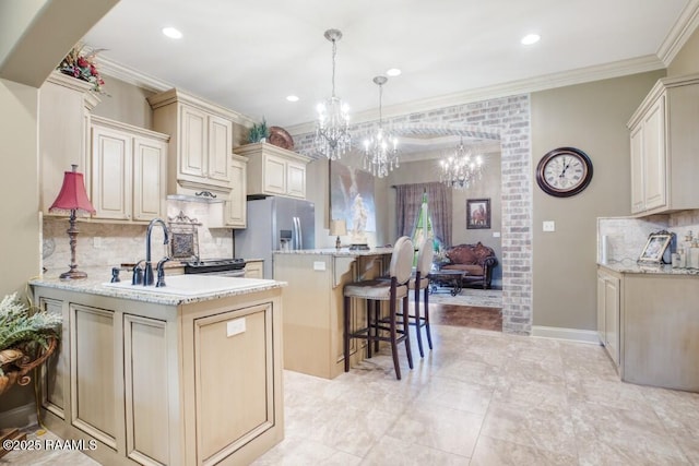 kitchen featuring a sink, stainless steel fridge with ice dispenser, backsplash, a chandelier, and ornamental molding