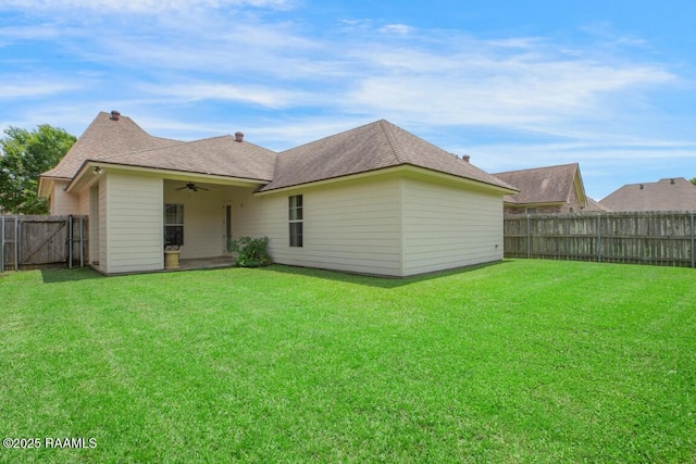 back of property featuring a fenced backyard, a ceiling fan, and a yard
