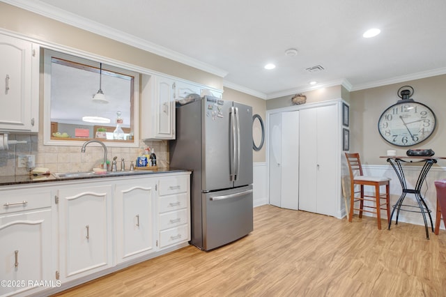 kitchen with freestanding refrigerator, light wood-style floors, ornamental molding, and a sink