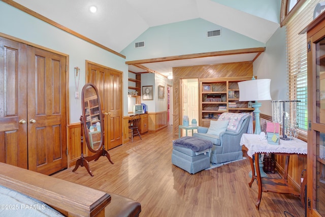 living room with high vaulted ceiling, wainscoting, visible vents, and wood finished floors