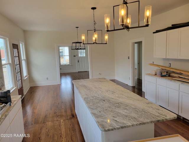 kitchen with white cabinetry, a kitchen island, an inviting chandelier, and dark wood-type flooring