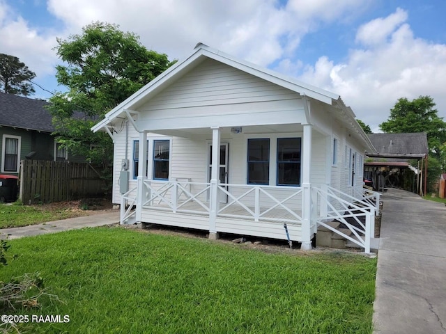 view of front of property featuring covered porch, fence, a front lawn, and driveway