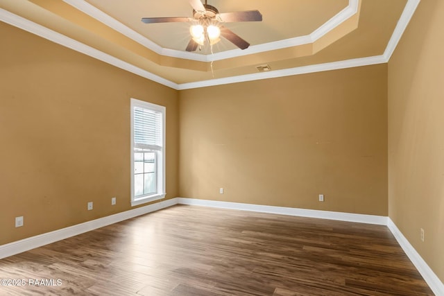unfurnished room featuring a tray ceiling, wood finished floors, a ceiling fan, crown molding, and baseboards