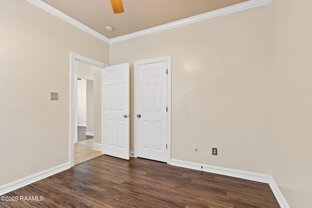 unfurnished bedroom with crown molding, wood finished floors, baseboards, and a ceiling fan