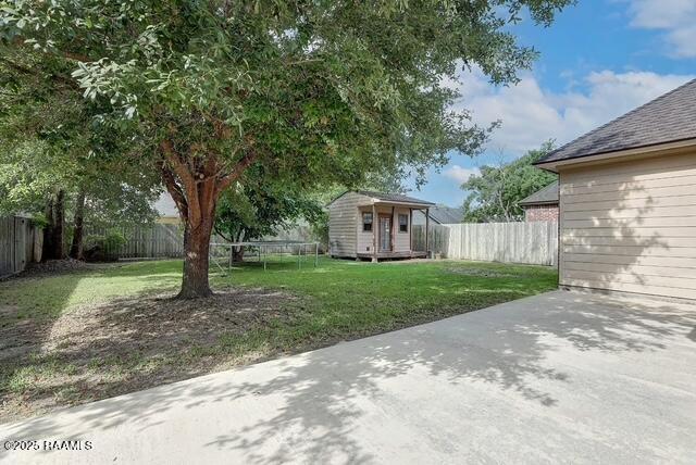 view of yard featuring a trampoline, an outdoor structure, a patio area, and a storage shed