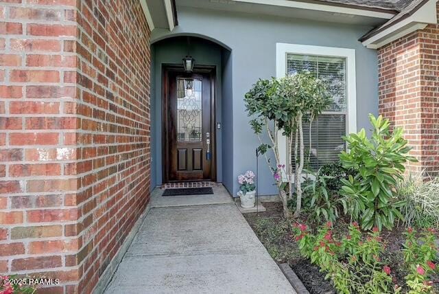 doorway to property with brick siding and stucco siding