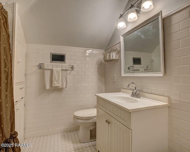 122 Lee St, New Iberia, LA 70560 - bathroom with tile walls, vanity, vaulted ceiling, toilet, and tile patterned floors
